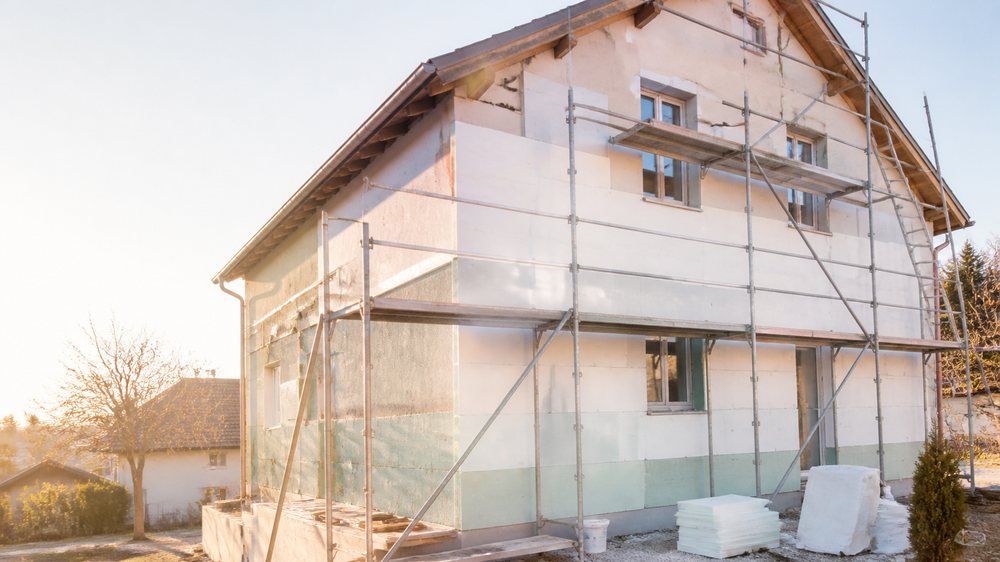 Façade d'une maison romande en cours d'isolation extérieure, échafaudage monté.